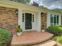 Inviting front porch featuring a dark-colored front door, decorative plants, and traditional brickwork at 6116 Springhouse Ln, Charlotte, NC 28211