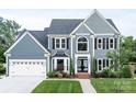 Charming two-story home showcasing a well-maintained lawn, black window shutters, and a two-car garage at 6400 Morningsong Ln, Charlotte, NC 28269