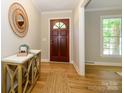Inviting home foyer featuring hardwood floors, a decorative mirror, and a wooden entry door at 7356 Terrace Dr, Charlotte, NC 28211