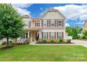 Charming two-story home with a cozy front porch, beautiful landscaping, and an American flag on display at 85017 Newloch Ct, Lancaster, SC 29720