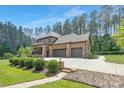 A two-car garage and large rear exterior of a brick home surrounded by mature trees at 102 Antioch Plantation Dr # 18, Matthews, NC 28104