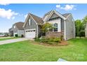 A charming exterior view showing a manicured lawn and stylish siding with stone accents on a sunny day at 12637 Belmont Mansion Dr, Charlotte, NC 28273