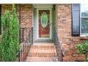 Close-up of the front door entrance featuring brick steps and iron railings, framed by manicured greenery at 2418 Live Oak Ct, Gastonia, NC 28056