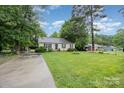 Inviting single-story home with a lush green lawn, mature trees, and a long driveway leading to the residence at 401 Yadkin St, Granite Quarry, NC 28072