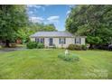 Well-kept single-story home featuring lush greenery, a manicured lawn, and a charming garden with a decorative statue at 401 Yadkin St, Granite Quarry, NC 28072
