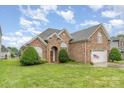 Beautiful brick home with manicured lawn, arched entrance, and two-car garage on a sunny day at 5052 Ashley Pl, Bessemer City, NC 28016