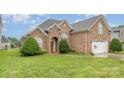Beautiful brick home with manicured lawn, arched entrance, and two-car garage on a sunny day at 5052 Ashley Pl, Bessemer City, NC 28016