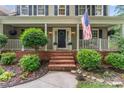 Inviting front porch with brick steps, American flag, landscaping, and decorative wreath on front door at 5233 Fairvista Dr, Charlotte, NC 28269