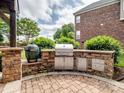 Outdoor kitchen featuring a built-in stone grill, stainless steel appliances, and a brick patio area at 538 Fairwoods Dr, Huntersville, NC 28078