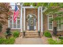 Inviting brick and stone entryway with American flag, elegant columns, and well-maintained landscaping at 7018 Dowington Dr, Charlotte, NC 28277
