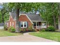 Quaint brick home featuring a cozy front porch and lush greenery surrounding the property at 725 W Graham St, Shelby, NC 28150