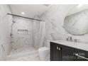 Modern bathroom featuring marble tile, walk-in shower, and dark vanity with round mirror at 8429 Meadowcroft Ct, Charlotte, NC 28215