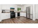 Bright kitchen with white cabinets, stainless steel appliances, and dark wood-look flooring at 8429 Meadowcroft Ct, Charlotte, NC 28215