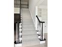 Stylish staircase with herringbone carpet runner, contrasting dark handrail, and open floor plan at 12711 Duncourtney Ln, Charlotte, NC 28277