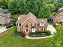 Well-manicured lawn and landscaping surround this two-story brick home with mature trees at 15737 Agincourt Dr, Huntersville, NC 28078
