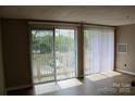 Bright living room with laminate floors and sliding door to balcony and outdoor view at 1604 Arlyn Cir # E, Charlotte, NC 28213