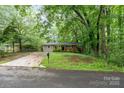 Quaint one-story home with a brick facade and a lawn, set among mature trees at 205 E Cleveland Ave, Bessemer City, NC 28016