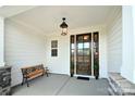 Inviting front porch featuring a dark wood door, bench seating, and elegant light fixtures at 3924 Dahlia Dr, Harrisburg, NC 28075