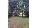 Lush backyard featuring green grass, mature trees, and parked car near a charming home at 5023 Dogwood Ln, Stanley, NC 28164