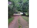 Long driveway leading to a charming house with a covered front porch surrounded by mature trees at 5023 Dogwood Ln, Stanley, NC 28164