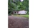 Charming single-story home with mature trees, a gravel driveway, and a covered front porch at 5023 Dogwood Ln, Stanley, NC 28164