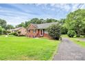 Beautiful brick home with lush green lawn, mature trees, and a welcoming red front door at 6908 Lancer Dr, Charlotte, NC 28226