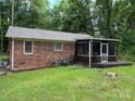 Back exterior view with a screened in back porch surrounded by a lush green lawn at 7316 Truelight Church Rd, Mint Hill, NC 28227