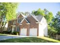 View of two-story brick home with a two-car garage and trimmed lawn at 7708 Harrington Woods Rd, Charlotte, NC 28269