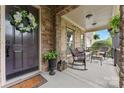 Inviting front porch with stone accents, seating, and a decorative wreath on the front door at 10620 Euclid Nw Ave, Concord, NC 28027