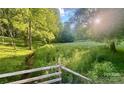 Lush backyard with a stream, a wooden fence, and lots of beautiful green foliage at 2130 Vashti Rd, Taylorsville, NC 28681