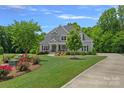 Landscaped front yard with blooming flowers and mature trees frames this beautiful two-story home at 224 Hidden Meadows Dr, Mooresville, NC 28117