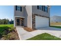 A close up of the exterior featuring stone accents and gray siding plus a large two car garage at 3064 Ora Smith Rd, Lincolnton, NC 28092