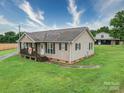 Cozy home featuring a covered front porch, green lawn, gravel driveway, and views of outbuilding at 4115 Jenkins Rd, Marshville, NC 28103