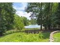 Scenic backyard view with lush greenery, a wooden fence, and a serene lake in the background at 4323 Rosecliff Dr, Charlotte, NC 28277