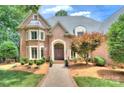Charming brick home featuring a manicured lawn, mature trees, and an inviting entrance with double doors and a brick walkway at 4323 Rosecliff Dr, Charlotte, NC 28277