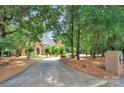 Beautiful brick home at the end of a tree-lined drive, featuring mature trees, lush landscape, and an inviting entrance at 4323 Rosecliff Dr, Charlotte, NC 28277