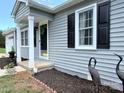Close-up of the front porch with gray siding, black shutters, and manicured flower beds at 5323 Flat Creek Rd, Heath Springs, SC 29058