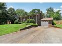 An exterior side-view of the traditional brick home with an attached garage and a paved driveway at 5626 Sandhurst Rd, Hickory, NC 28602
