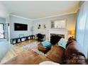 Inviting living room with hardwood floors, fireplace, flat-screen TV, and comfortable brown sectional couch at 5947 Quail Hollow Rd # A, Charlotte, NC 28210