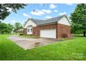 A brick home with a two-car garage and an expansive driveway surrounded by lush green lawns and mature trees at 7189 Bovine Ln # 28, Harrisburg, NC 28075