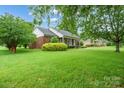 Brick home featuring a lush green lawn, complemented by mature trees for privacy and shade at 7189 Bovine Ln # 28, Harrisburg, NC 28075