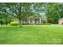 Beautiful home with a well-manicured lawn, mature trees, and a welcoming front porch with columns at 7189 Bovine Ln # 28, Harrisburg, NC 28075
