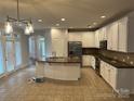 Open kitchen with white cabinets, granite countertops, stainless appliances, and a central island at 10715 Tom Short Rd, Charlotte, NC 28277