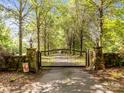 Grand entrance featuring a secure iron gate, stone pillars, and a welcoming, tree-lined driveway at 1433 Kern Carlton Rd, Salisbury, NC 28146