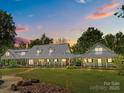 Stunning dusk view of a spacious home with a metal roof and inviting wraparound porch, set on a sprawling lawn at 1433 Kern Carlton Rd, Salisbury, NC 28146