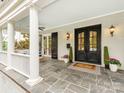 Inviting front porch with stone flooring, white columns, and double doors with sidelights at 1600 Princeton Ave, Charlotte, NC 28209