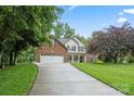 View of a driveway leading to a beautiful two-story home surrounded by lush greenery on a sunny day at 1730 Eden Glen Dr, Dallas, NC 28034