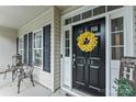 Welcoming front door with a wreath, black hardware, and a charming porch setting with a 'Welcome to our home' sign at 1730 Eden Glen Dr, Dallas, NC 28034