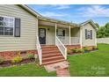 Inviting front porch with wooden stairs and white railing, set against brick foundation at 3125 Leonard Dr, Gastonia, NC 28056