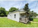 Exterior side view of cozy home featuring a covered front porch and green lawn at 502 E Main St, Cleveland, NC 27013